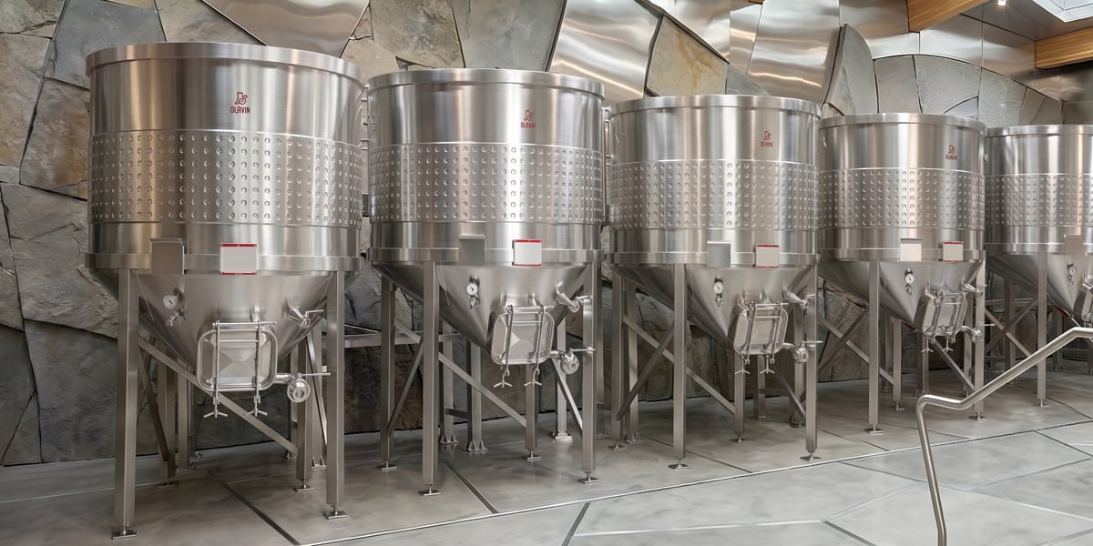 Olavin open-top conical fermenters on a polished stone cellar floor
