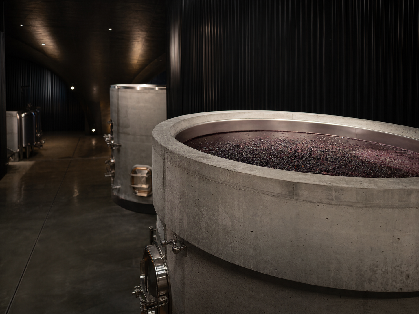 Open-top fermentation tank in a quiet dark winery cellar.